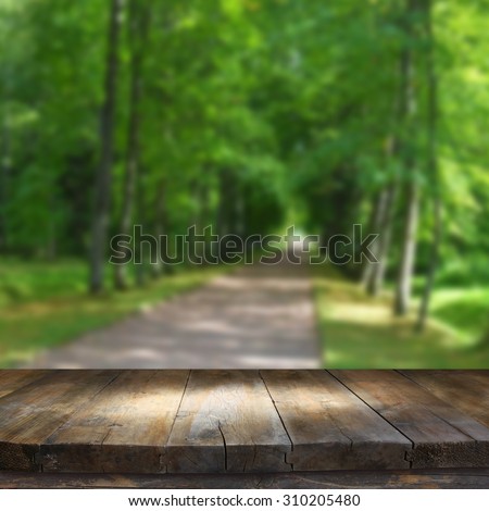 vintage wooden board table in front of dreamy and abstract forest landscape 