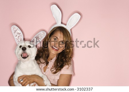 Caucasian prime adult female and white terrier dog wearing rabbit ears.