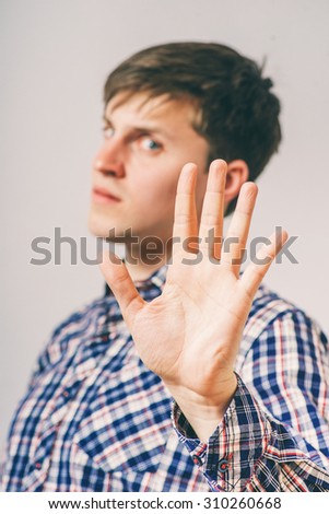 guy shows a gesture stop. On a gray background.