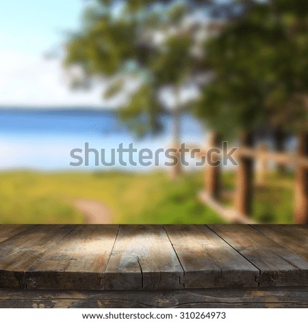 vintage wooden board table in front of dreamy and abstract forest lake landscape with lens flare.
