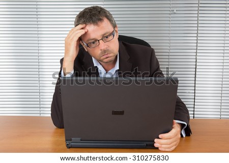 Handsome serious unshaven  man sitting looking directly at his computer