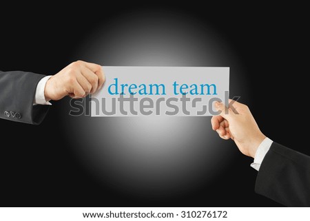Close-up Of Two Businessman's Hand Holding Paper With Dream Team Word On It