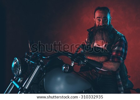 Cool man with long gray beard on motorcycle at night.