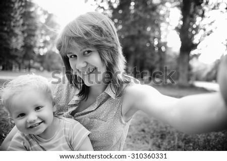 Black and white photo of happy family mother and her adorable toddler son at park making selfie