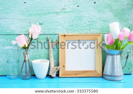 Vintage blank wooden frame, bottles ,flower on paint wood background.