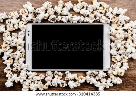 Tablet pc on wood with attributes of cinema. Visual metaphor for content consumption - films and media on a mobile device.