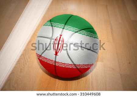 basketball ball with the national flag of iran lying on the floor near the white line
