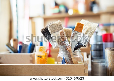 Paint brushes and crafting supplies on the table in a workshop. Royalty-Free Stock Photo #310459523