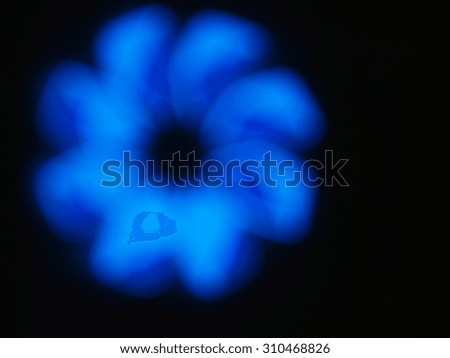 Blurred and defocused image of an abstract blue shapes closeup of the glowing neon lights on a black background