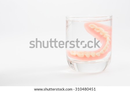 a denture is cleaned in a glass of water. proper hygiene.