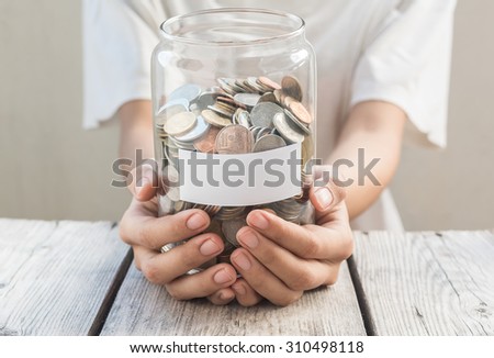 Money jar with coins and Clock on wood table , Saving Concept