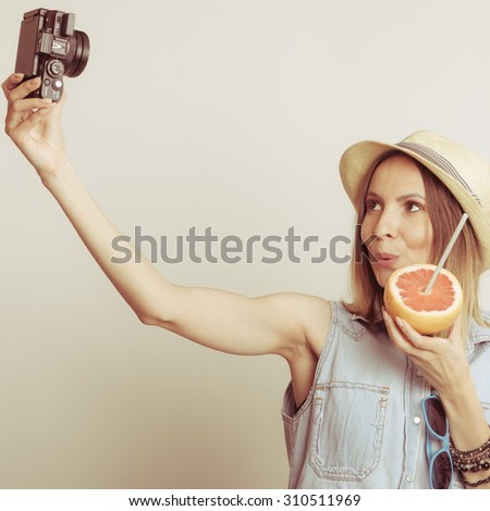 Happy tourist woman in straw hat taking selfie self picture with camera while holding grapefruit fruit in hand. Summer vacation holiday.