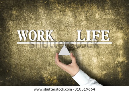 Work Life Balance concept with scale holden by businessman hand against the old background.