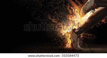 Sport. Runner. Side view of a jogger legs with the power in the veins  isolated on black. Fire and energy Royalty-Free Stock Photo #310584473