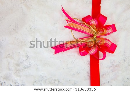 Decorative simple gold ribbon and bow on a background of winter snow with copyspace for your Christmas or festive greeting,Christmas team