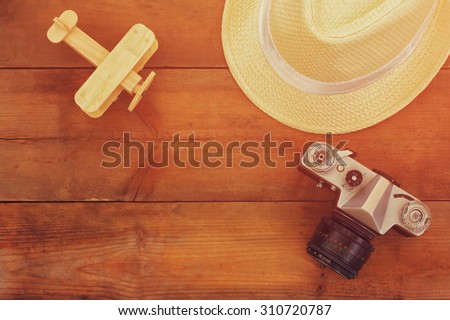 top view image of  wood aeroplane, fedora hat and old camera over wooden table