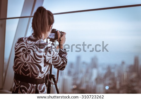 Young woman takes a picture of city at Bangkok Thailand vintage color 
