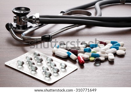 A Stethoscope and medicines are on a brown desk