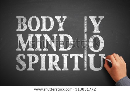 Hand with chalk is writing the concept of Body Mind Spirit You on the blackboard.