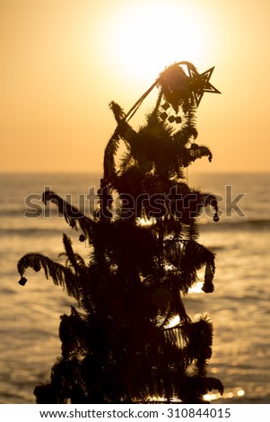 Silhouette of an old christmas tree standing by the beach with ocean and a beautiful sunset in Miraflores. Lima - Peru