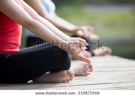 Close up of hands of two beautiful sporty fit young women meditating or breathing outdoors, Sitting in Easy (Pleasant Posture), Sukhasana, wearing sportswear working out on summer day Royalty-Free Stock Photo #310875968