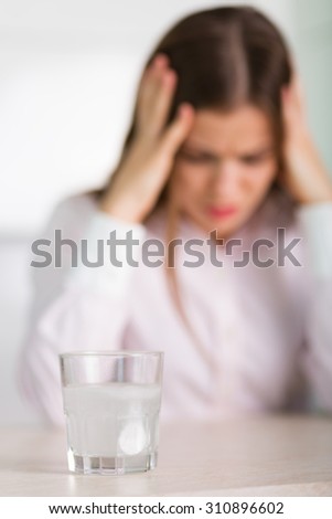Glass of water with a dissolving pain reliever pill
