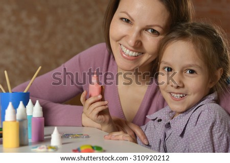 Portrait of a little girl painting with her mother