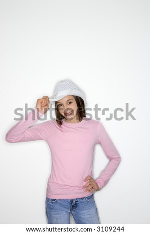 Portrait of Asian-American teen girl tipping cowboy hat and hand on hip standing against white background.