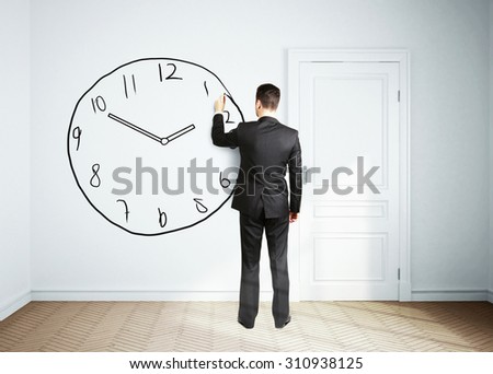 businessman drawing clock on wall