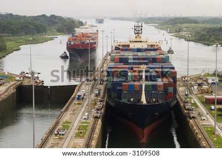 Several freighters, assisted by tugboats, are entering the Panama Canal at Gatun Locks on the Atlantic side. These container ships are fully loaded with cargo heading west towards the Pacific. Royalty-Free Stock Photo #3109508