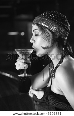 Caucasian prime adult retro female sitting at bar drinking martini.