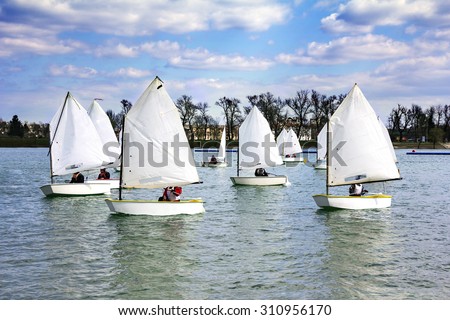 Lots of Small white boats sailing on the lake 