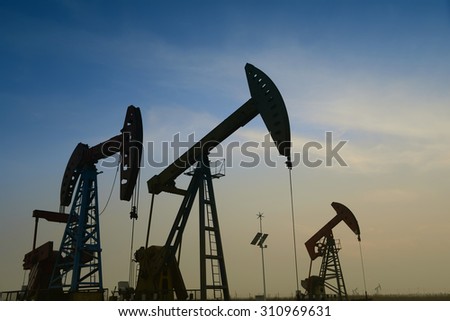 Many are operation of pumping unit in oil field in the evening 