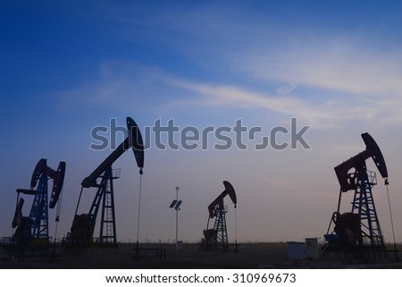 Many are operation of pumping unit in oil field in the evening 