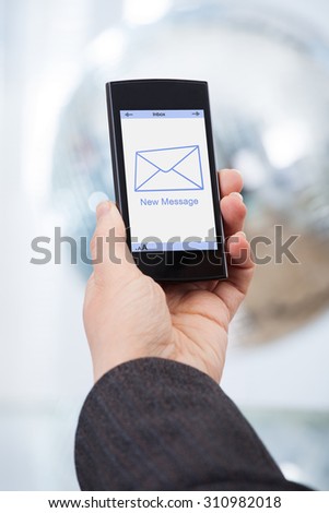 Cropped image of businesswoman's hand holding smartphone with new message on screen