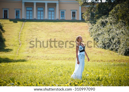 Pretty young blonde girl near gorgeous house with columns in a summer