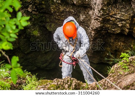 Caver descends into the cave Royalty-Free Stock Photo #311004260