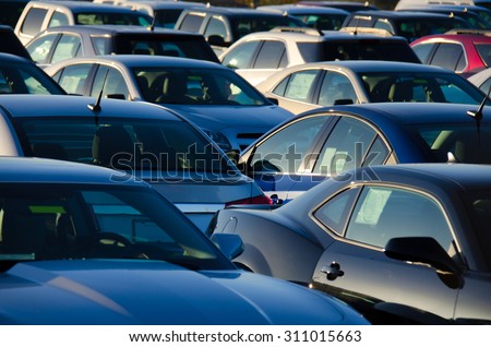 Sunrise at a jam packed parking sales lot with many rows of automobiles. Royalty-Free Stock Photo #311015663