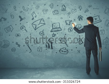 Businessman drawing a media icons on a wall