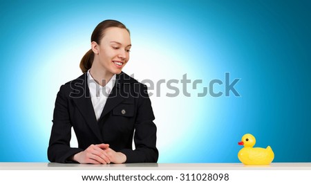 Young businesswoman and yellow rubber duck toy on table