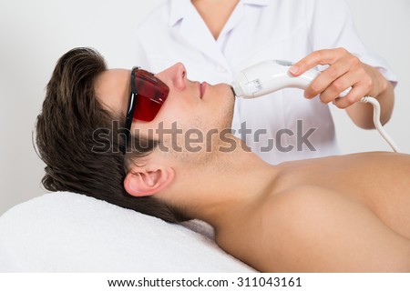 Young Man Receiving Laser Hair Removal Treatment At Beauty Center Royalty-Free Stock Photo #311043161