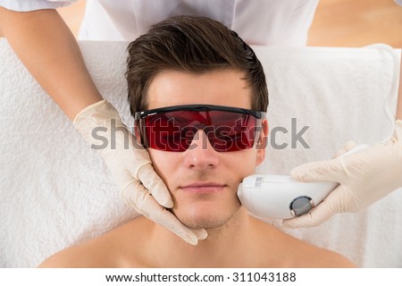 Close-up Of Beautician Giving Laser Epilation Treatment To Young Man Face Royalty-Free Stock Photo #311043188