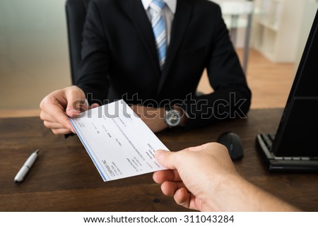 Close-up Of Businessman Hands Giving Cheque To Other Person In Office Royalty-Free Stock Photo #311043284