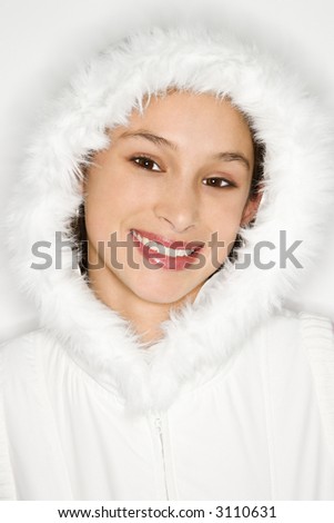 Portrait of Asian-American teen girl wearing fur lined coat hood and smiling against white background.