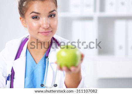 Female doctor hand holding a green apple, standing 