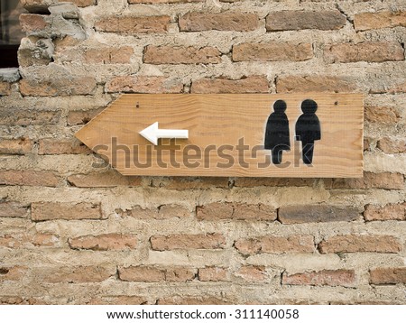 toilet sign on plain brick wall
