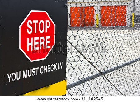 Stop sign with check in posted on a metal fence.