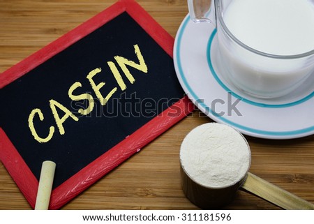 Casein written on chalkboard with a cup of milk and a scoop of milk powder on wood background Royalty-Free Stock Photo #311181596