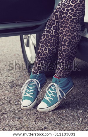 The woman rising out of the car with blue sneakers in Finland. She is wearing a leopard-print pants. Image includes a effect.