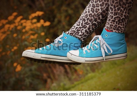 Woman waving her legs in the air in Finland. She is wearing a leopard-print pants and blue sneakers. Image includes a effect.